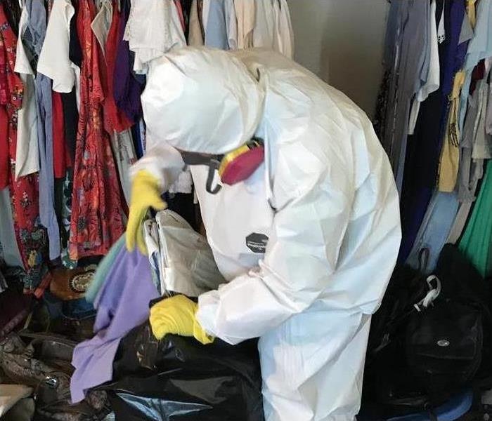 man in white PPE putting clothes in bag