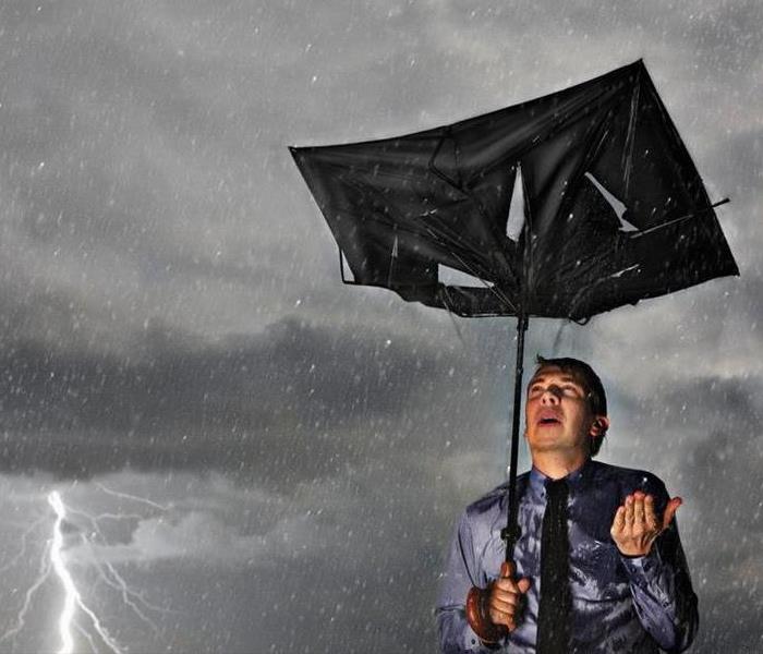 a picture of a man with a broken umbrella in a lightning storm
