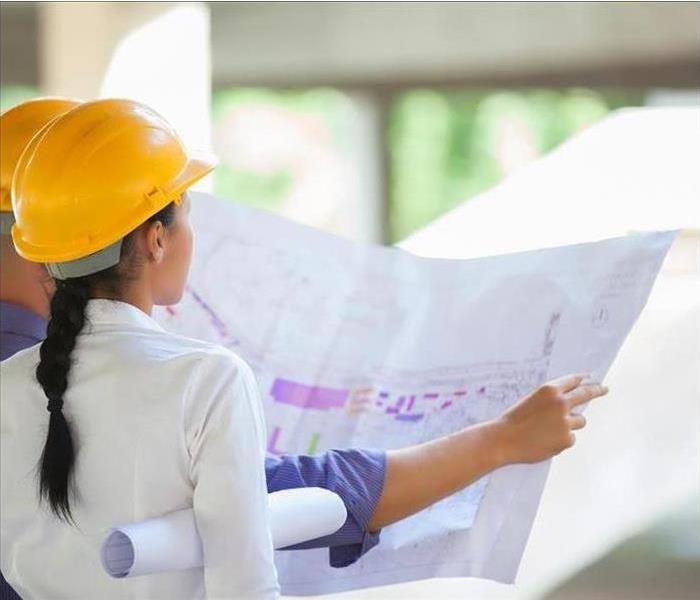 a picture of a woman looking at construction plans